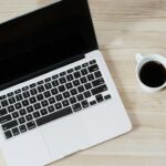 turned off MacBook Pro beside white ceramic mug filled with coffee