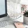 turned-on Asus laptop near eyeglasses, succulent plant, and empty clear glass bottle