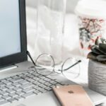 turned-on Asus laptop near eyeglasses, succulent plant, and empty clear glass bottle