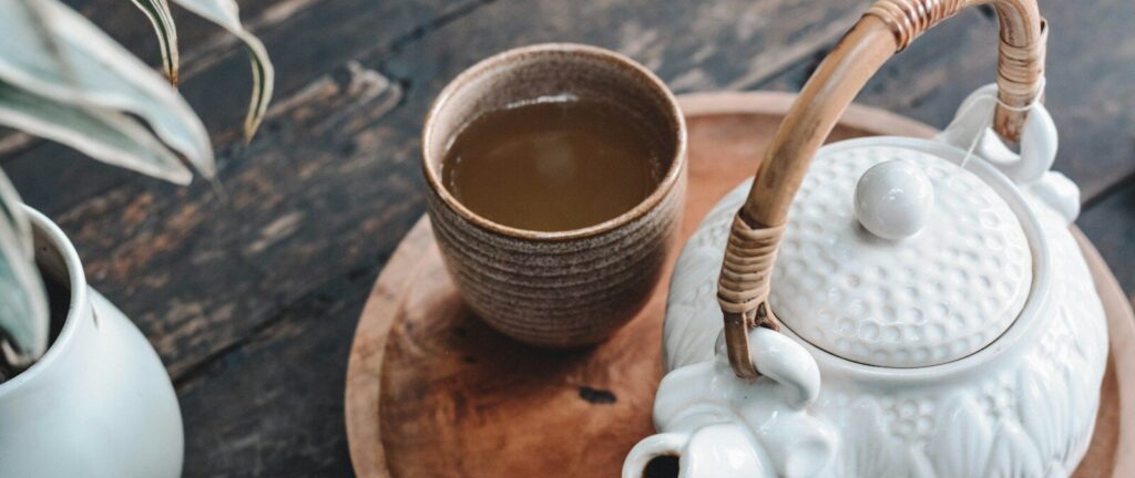 white and brown ceramic teapot on wooden tray