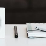 white desk clock near pen and book