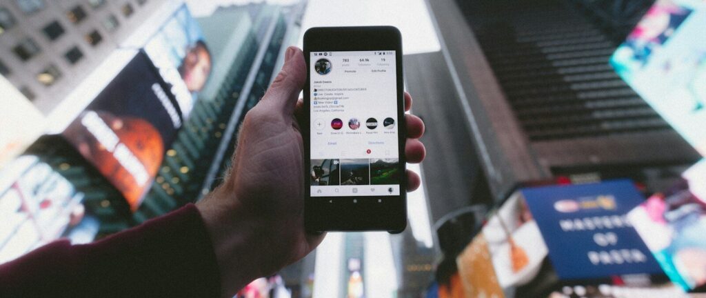 high angle photo of person holding turned on smartphone with tall buildings background