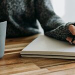 a person holding a pen and writing on a notebook