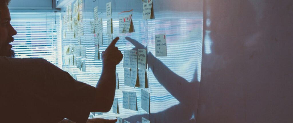 person pointing white paper on wall