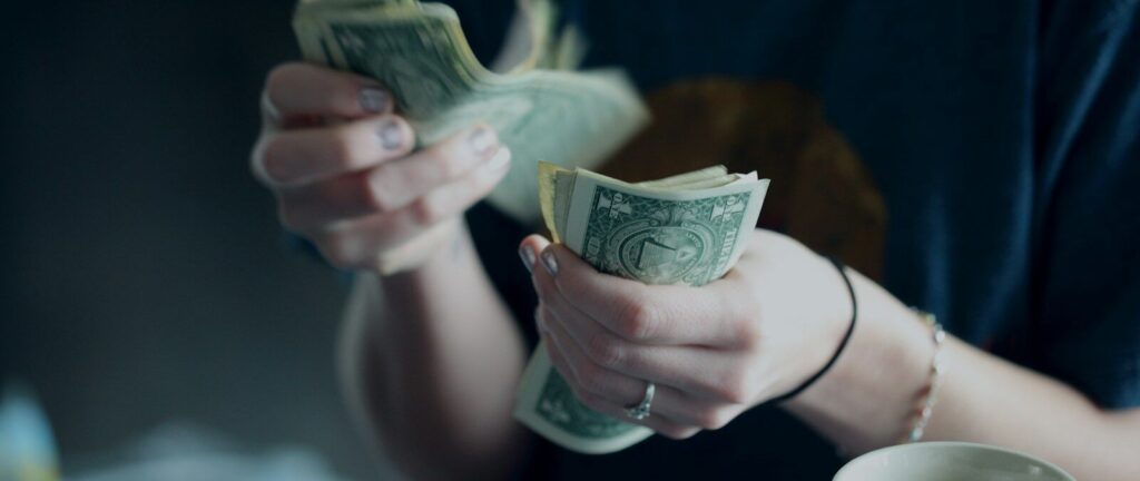 focus photography of person counting dollar banknotes