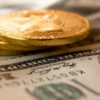 three round gold-colored coins on 100 US dollar banknotes