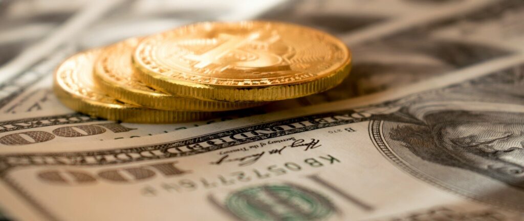 three round gold-colored coins on 100 US dollar banknotes
